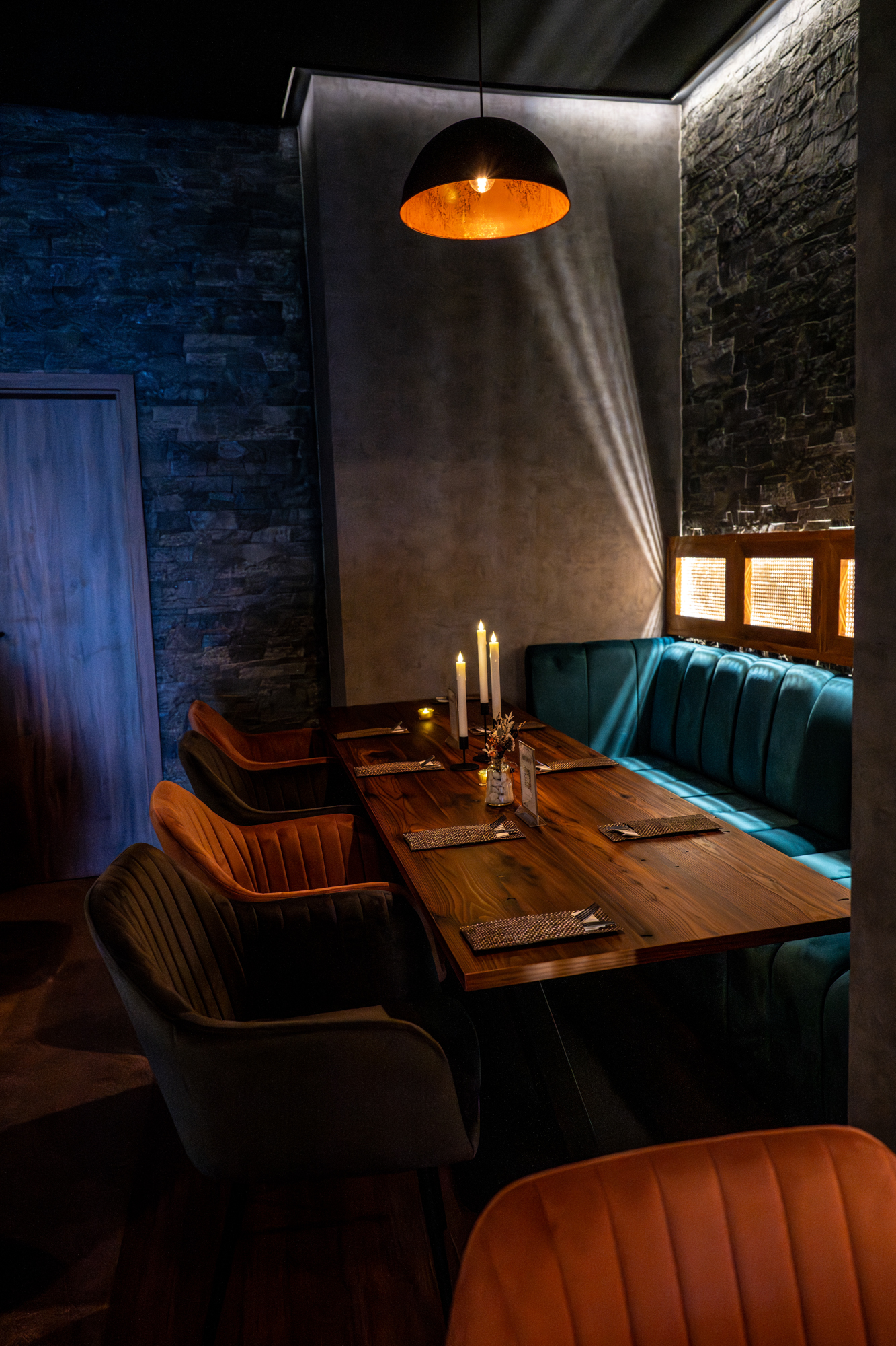 Stilvoll gedeckter Tisch im BLOOM Restaurant mit Kerzenlicht, türkisfarbenem Sitzbereich und warmer Hängeleuchte